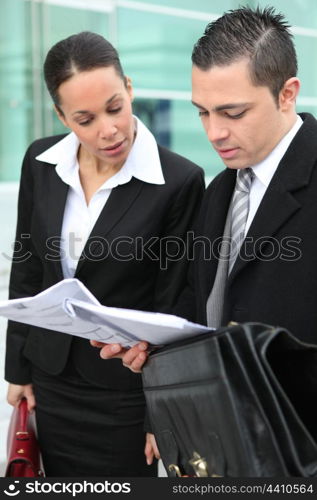 Business couple examining documents outside
