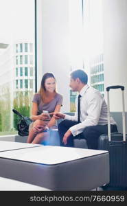 Business couple talking while sitting and waiting in hotel reception area