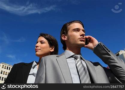 Business couple using a cellphone outside