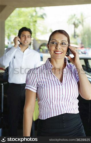 Business couple using mobile phones outdoors