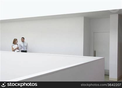 Business couple walking through office hallway, side view