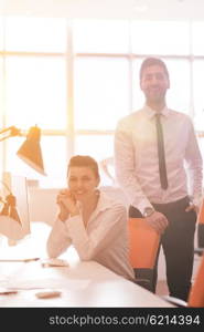 business couple working together on project at modern startup office. Early morning scene with sun flare in background