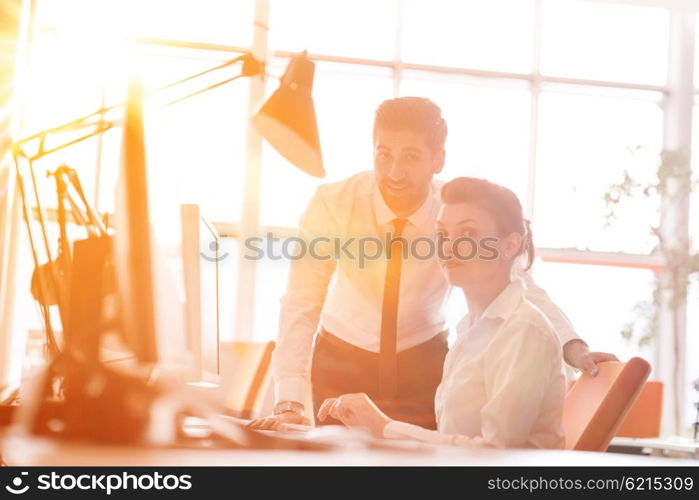 business couple working together on project at modern startup office. Early morning scene with sun flare in background