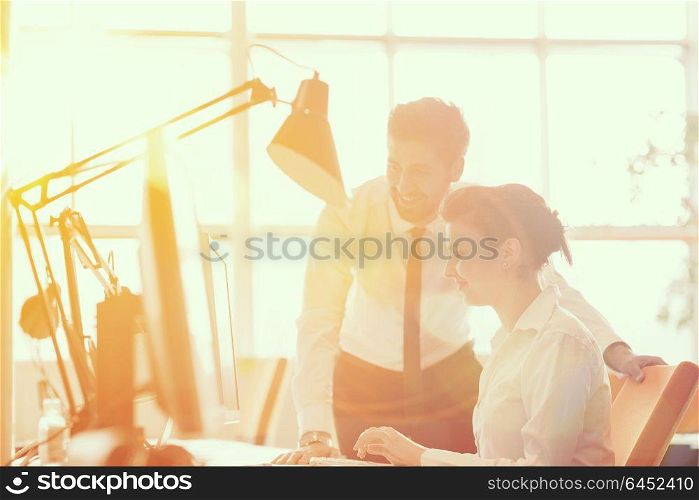 business couple working together on project at modern startup office. Early morning scene with sun flare in background