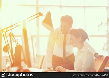 business couple working together on project at modern startup office. Early morning scene with sun flare in background