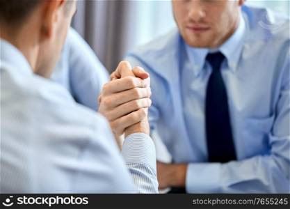 business, crisis and confrontation concept - close up of people arm wrestling at office. close up of businesspeople arm wrestling at office