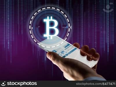 business, cryptocurrency and future technology concept - close up of businessman hand with charts on transparent smartphone and bitcoin hologram over binary code on ultra violet background. hand with smartphone and bitcoin hologram. hand with smartphone and bitcoin hologram