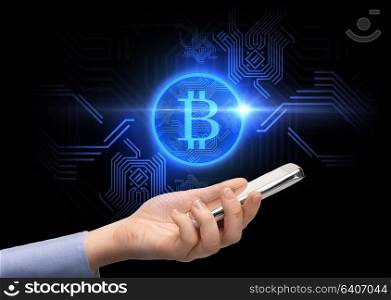 business, cryptocurrency and future technology concept - close up of female hand holding smartphone with virtual bitcoin symbol hologram over black background. close up of hand with smartphone and bitcoin