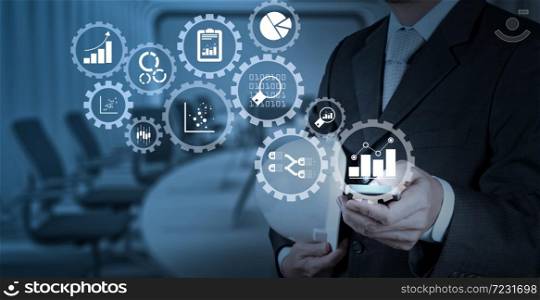 Business data analytics management with connected gear cogs with KPI financial charts and graph.Businessman hand working with a digital tablet on meeting room background