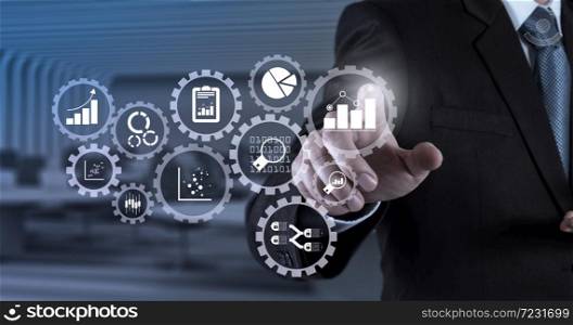 Business data analytics management with connected gear cogs with KPI financial charts and graph.Businessman hand pressing an imaginary button on virtual screen