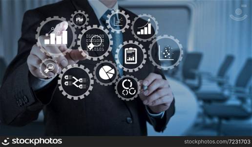 Business data analytics management with connected gear cogs with KPI financial charts and graph.Businessman hand pressing an imaginary button on virtual screen.