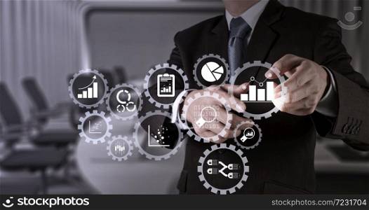 Business data analytics management with connected gear cogs with KPI financial charts and graph.Businessman hand pressing an imaginary button on virtual screen