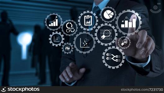 Business data analytics management with connected gear cogs with KPI financial charts and graph.Businessman hand pressing an imaginary button on virtual screen.