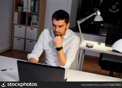 business, deadline and people concept - businessman with laptop computer working at night office. businessman with laptop working at night office