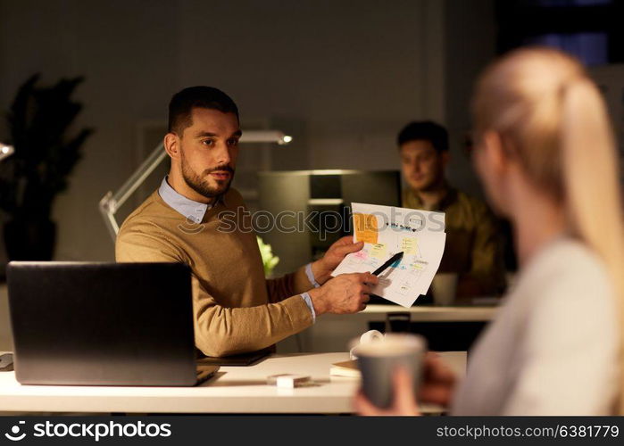 business, deadline and people concept - colleagues discussing project late at night office. colleagues discussing project late in office