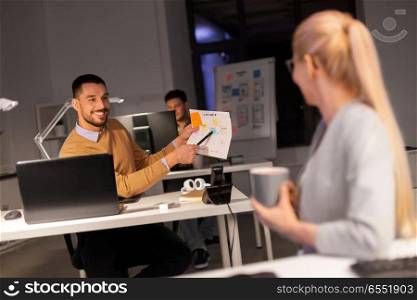 business, deadline and people concept - man showing papers to colleague late at night office. business team with papers working late at office. business team with papers working late at office