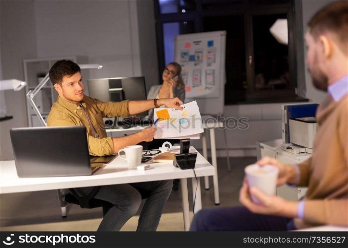 business, deadline and people concept - man showing papers to colleague late at night office. business team with papers working late at office