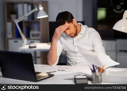 business, deadline and stress concept - businessman with papers working at night office. businessman with papers working at night office