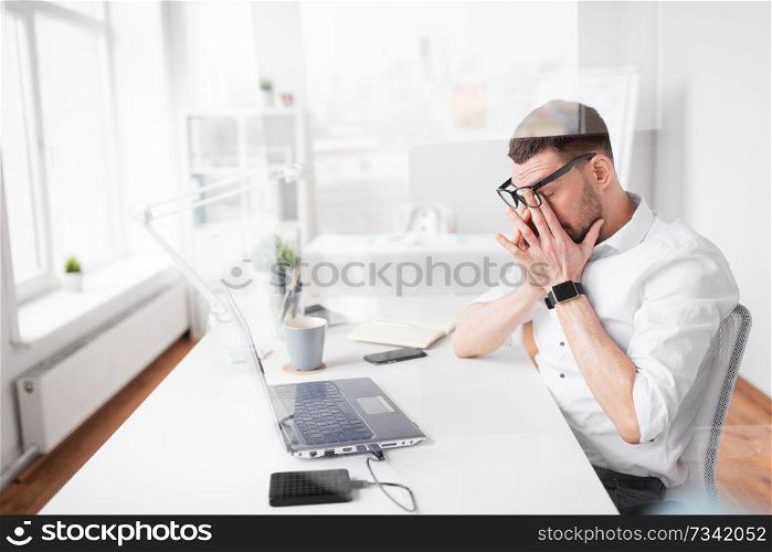 business, deadline and stress concept - tired businessman rubbing eyes at office. tired businessman rubbing eyes at office