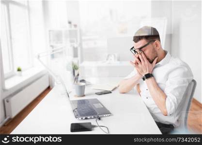 business, deadline and stress concept - tired businessman rubbing eyes at office. tired businessman rubbing eyes at office