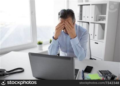 business, deadline and stress people concept - stressed businessman with laptop working at office. stressed businessman with laptop working at office
