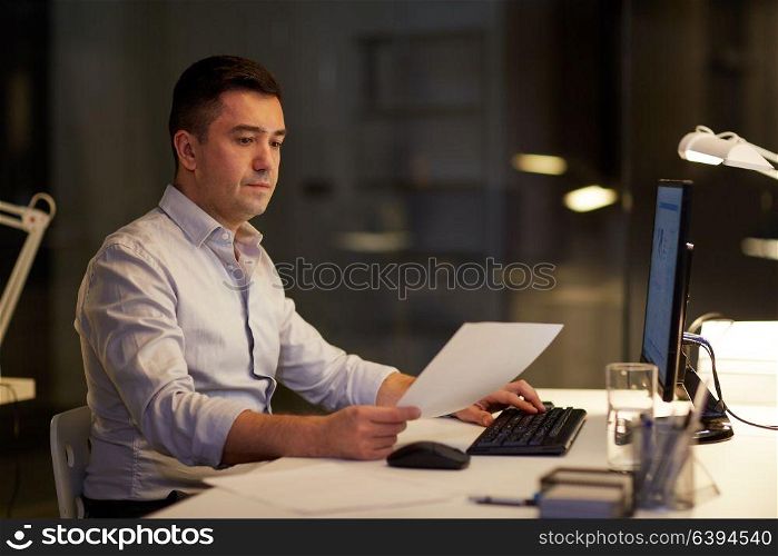 business, deadline and technology concept - businessman with computer and working at night office. businessman with computer working at night office