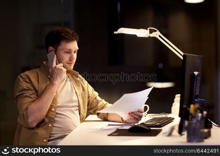 business, deadline and technology concept - businessman with papers calling on sartphone at night office. businessman calling on sartphone at night office