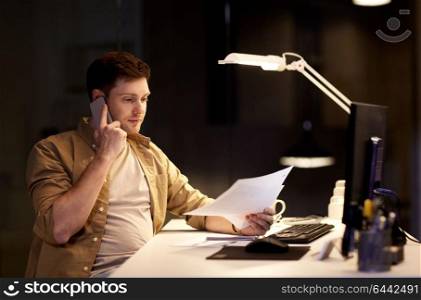 business, deadline and technology concept - businessman with papers calling on sartphone at night office. businessman calling on sartphone at night office