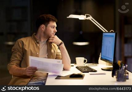 business, deadline and technology concept - businessman with papers working at night office. businessman with papers working at night office