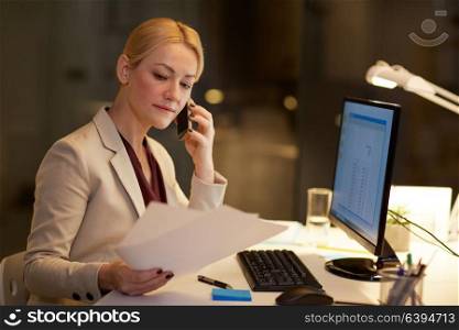 business, deadline and technology concept - businesswoman calling on smartphone with papers and computer at night office. businesswoman calling on smartphone at office
