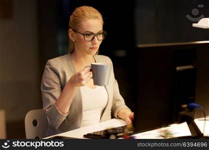 business, deadline and technology concept - businesswoman with computer working at night office and drinking coffee. businesswoman at night office drinking coffee