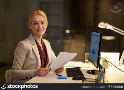 business, deadline and technology concept - businesswoman with papers and computer working at night office. businesswoman with papers working at night office