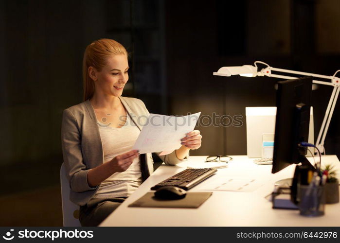 business, deadline and technology concept - businesswoman with papers and computer working at night office. businesswoman with papers working at night office