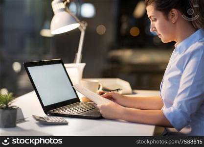 business, deadline and technology concept - businesswoman with papers and computer working at night office. businesswoman with papers working at night office
