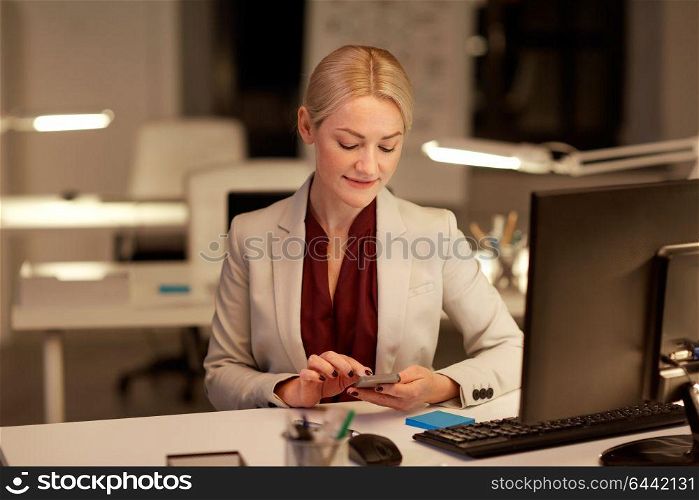 business, deadline and technology concept - businesswoman with smartphone and computer working at night office. businesswoman with smartphone at night office