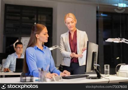 business, deadline and technology concept - businesswomen discussing charts late at night office. businesswomen discussing charts at night office