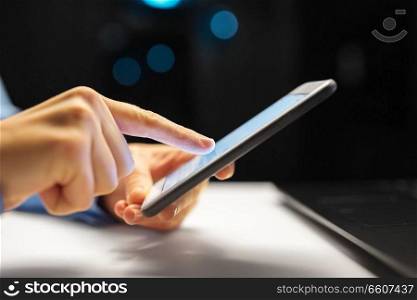 business, deadline and technology concept - close up of businesswoman hands with smartphone at night office. close up of hands with smartphone at night office