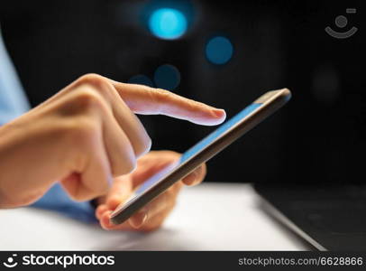 business, deadline and technology concept - close up of businesswoman hands with smartphone at night office. close up of hands with smartphone at night office