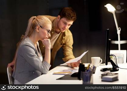 business, deadline and technology concept - coworkers with papers working late at night office. business team with papers working at night office. business team with papers working at night office