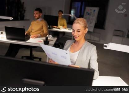 business, deadline and technology concept - designer or user interface developer with papers working at night office. designer working with papers at night office. designer working with papers at night office