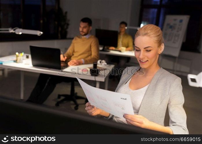 business, deadline and technology concept - designer or user interface developer with papers working at night office. designer working with papers at night office