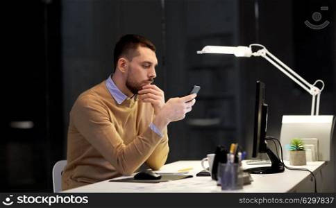 business, deadline and technology concept - man with smartphone and computer working at night office. man with smartphone working late at night office. man with smartphone working late at night office