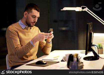 business, deadline and technology concept - man with smartphone and computer working at night office. man with smartphone working late at night office
