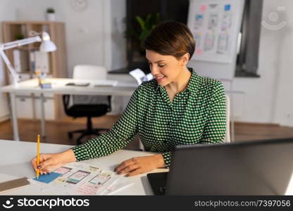 business, deadline and ui design concept - creative woman with user interface templates working at night office. woman working on user interface at night office