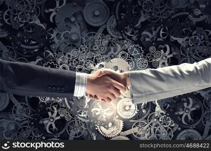 Business deal. Business partners handshake and gears mechanism on background