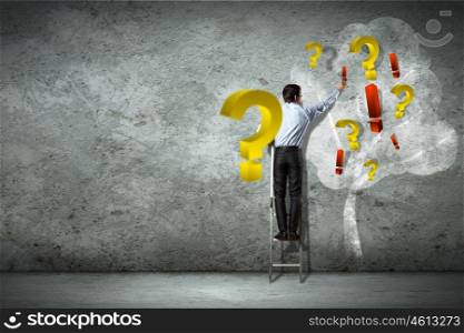 Business decision making. Image of businessman standing on ladder against question signs
