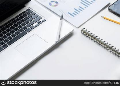 Business desk with a keyboard, report graph chart, pen and tablet on white table.