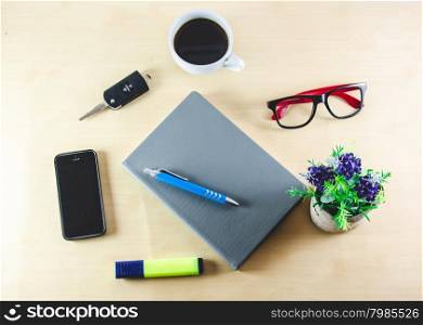 Business desk with coffee, book and pen on wooden table