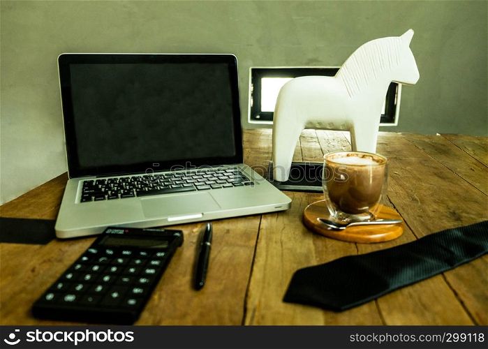 Business desktop , workspace with laptop,cup of coffee,calculator,necktie and pen on the woodtable.
