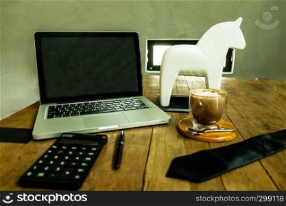 Business desktop , workspace with laptop,cup of coffee,calculator,necktie and pen on the woodtable.